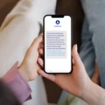 Persona sosteniendo un teléfono móvil mostrando un mensaje de WhatsApp.