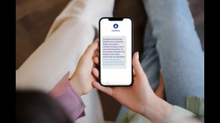 Persona sosteniendo un teléfono móvil mostrando un mensaje de WhatsApp.
