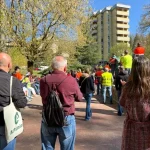 Grupo de personas reunidas en un parque con edificios al fondo