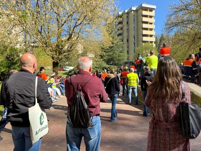 Grupo de personas reunidas en un parque con edificios al fondo
