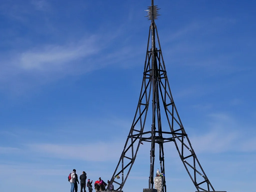 Grupo de personas junto a la cruz del Gorbea bajo un cielo azul