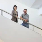 Dos personas posando en una escalera moderna y luminosa.