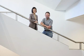 Dos personas posando en una escalera moderna y luminosa.