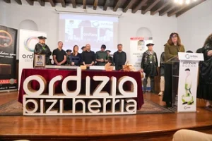 Mesa de presentación con logotipos y personas en Ordizia