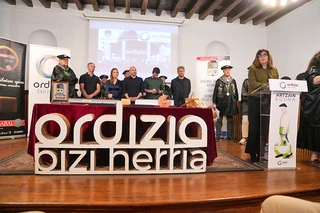 Mesa de presentación con logotipos y personas en Ordizia
