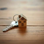 Llave y miniatura de casa sobre una mesa de madera