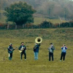 Grupo musical tocando instrumentos en un campo verde