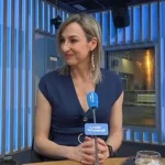 Mujer con blusa azul sentada en un set de televisión