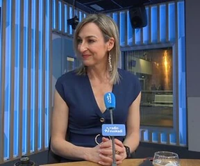 Mujer con blusa azul sentada en un set de televisión