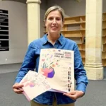 Mujer sosteniendo un cartel y un folleto de Días de Libro 2026