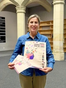 Mujer sosteniendo un cartel y un folleto de Días de Libro 2026