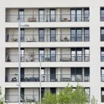 Fachada de un edificio moderno con balcones y plantas.