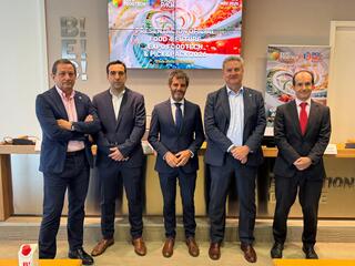 Cinco hombres de pie en un evento, fondo con pantallas