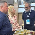 Tres personas conversan sobre productos gastronómicos en un evento