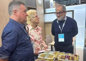 Tres personas conversan sobre productos gastronómicos en un evento