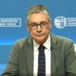 Hombre con gafas y chaqueta en conferencia de prensa