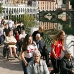 Grupo de personas en sillas de ruedas paseando junto a un río.