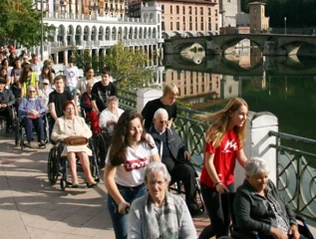Grupo de personas en sillas de ruedas paseando junto a un río.