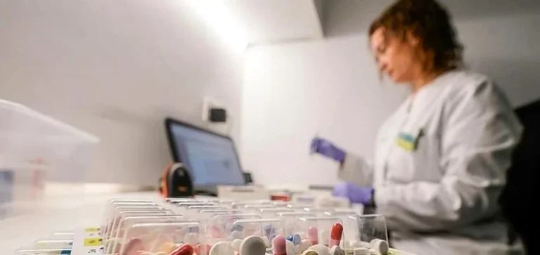 Mujer organizando pastilleros personalizados en una mesa