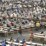 Gran cantidad de personas en mesas durante un examen masivo