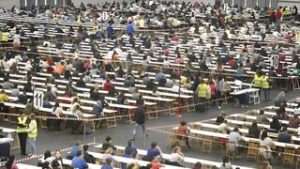Gran cantidad de personas en mesas durante un examen masivo