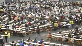 Gran cantidad de personas en mesas durante un examen masivo