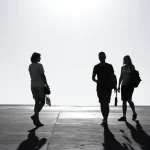 Siluetas de tres personas caminando al atardecer