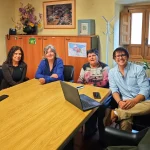 Cuatro personas sentadas alrededor de una mesa con un ordenador portátil