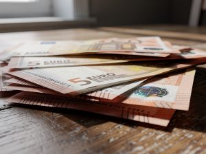 Billetes de cinco euros apilados sobre una mesa de madera.