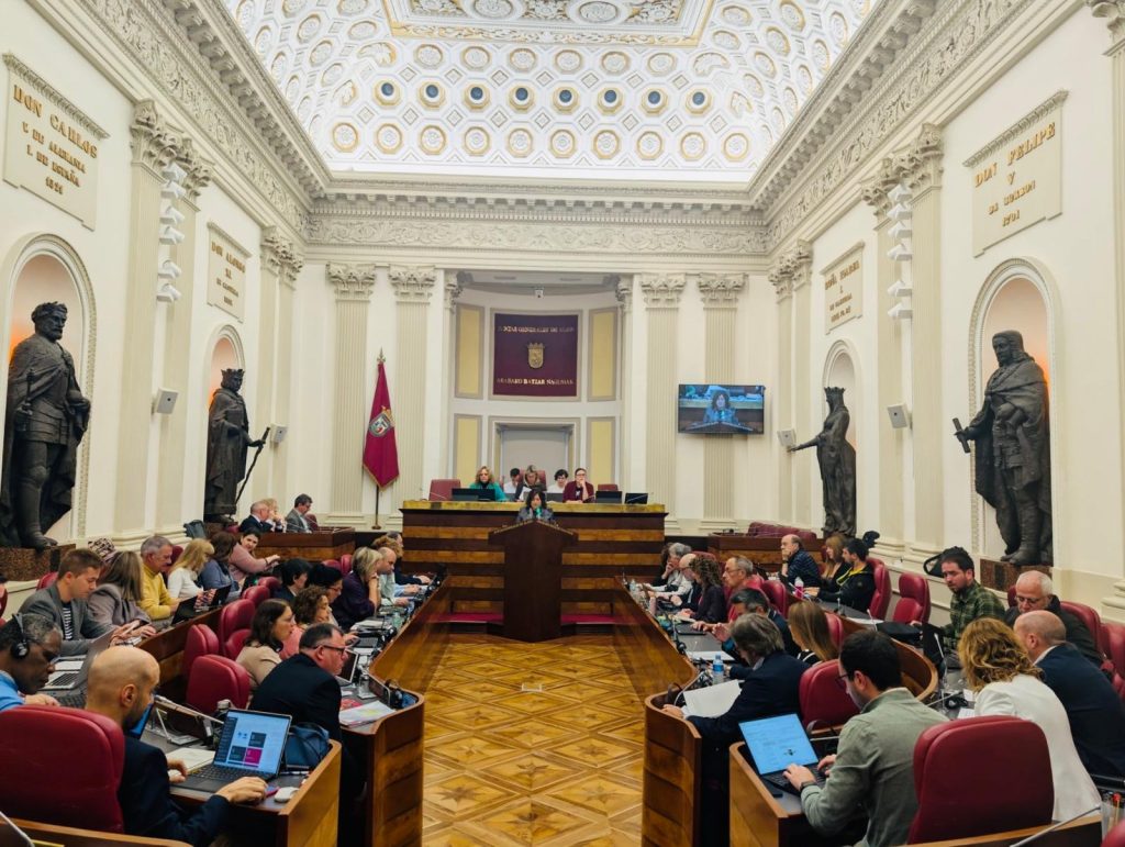 Sala de pleno con representantes debatiendo en Araba.