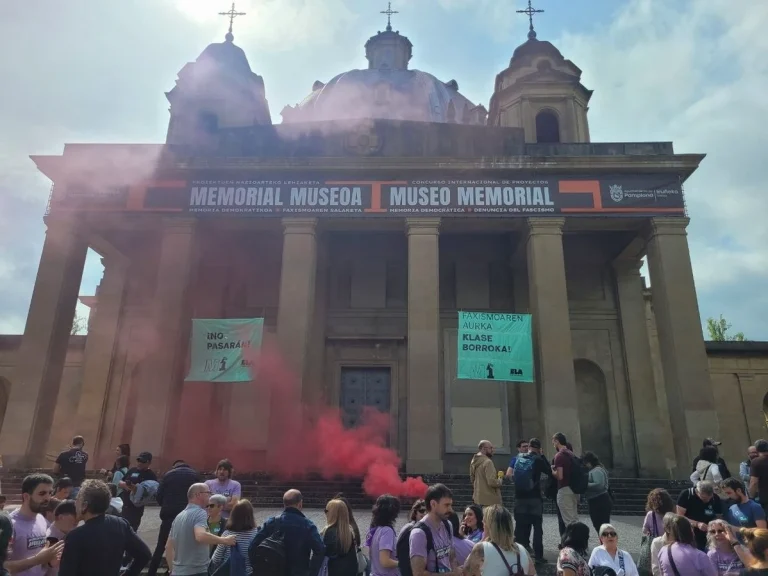 Edificio con humo rojo y manifestantes en el Primero de Mayo