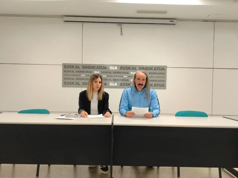 Dos personas sentadas en una mesa con documentos en mano.