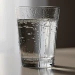 Vaso de agua con burbujas en una mesa iluminada