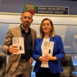 Dos personas sosteniendo documentos en un evento oficial del Gobierno Vasco.