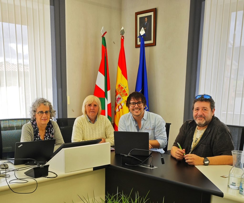 Reunión en el Ayuntamiento de Iruña de Oca con cuatro personas y banderas