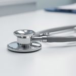 Estetoscopio sobre una mesa blanca en un entorno médico.