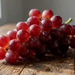 Racimo de uvas rojas sobre una mesa de madera
