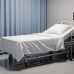 Cama de hospital con sábanas blancas y monitor médico.