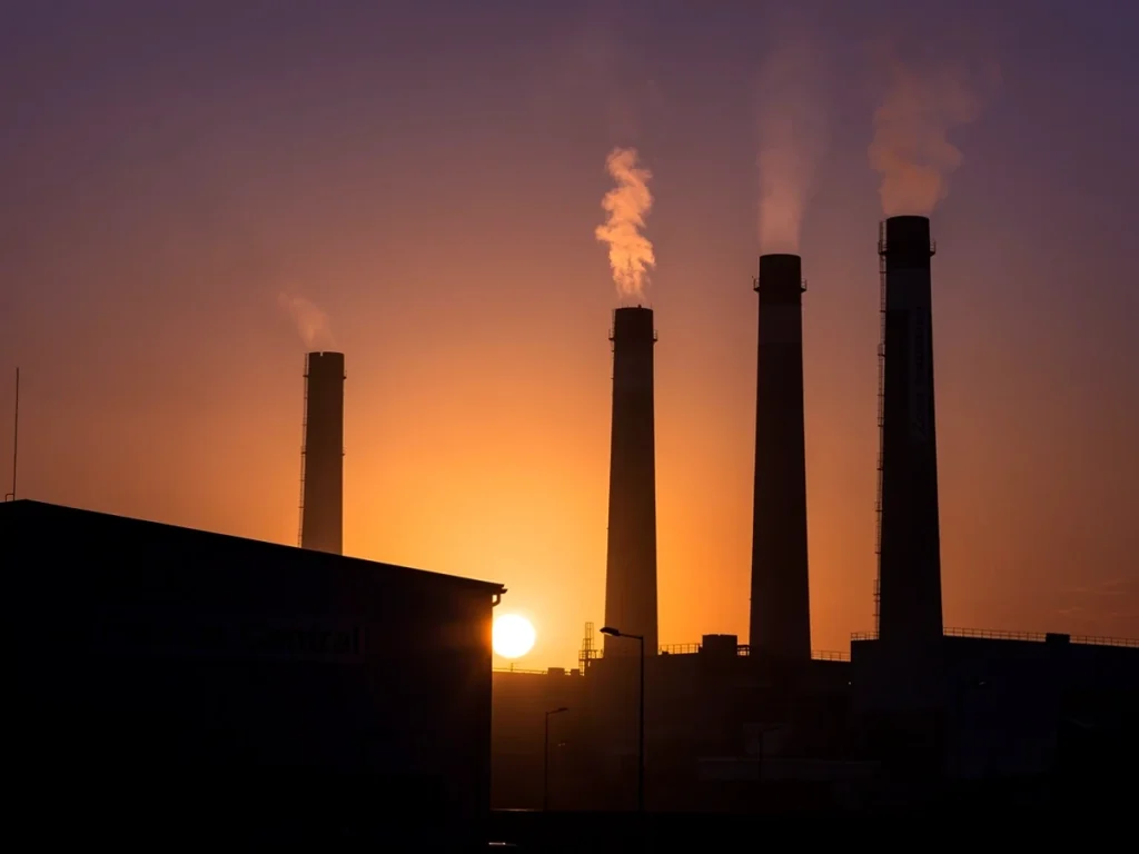 Silhouette de chimeneas industriales al atardecer con humo
