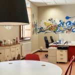 Oficina moderna con mesa, sillas y mural colorido