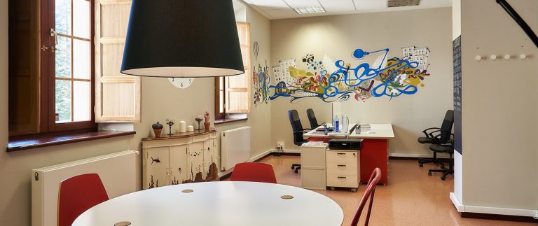 Oficina moderna con mesa, sillas y mural colorido