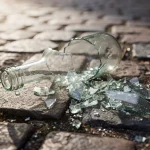 Botella de cristal rota sobre un pavimento de piedra