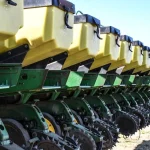 Fila de sembradoras agrícolas amarillas y verdes en el campo