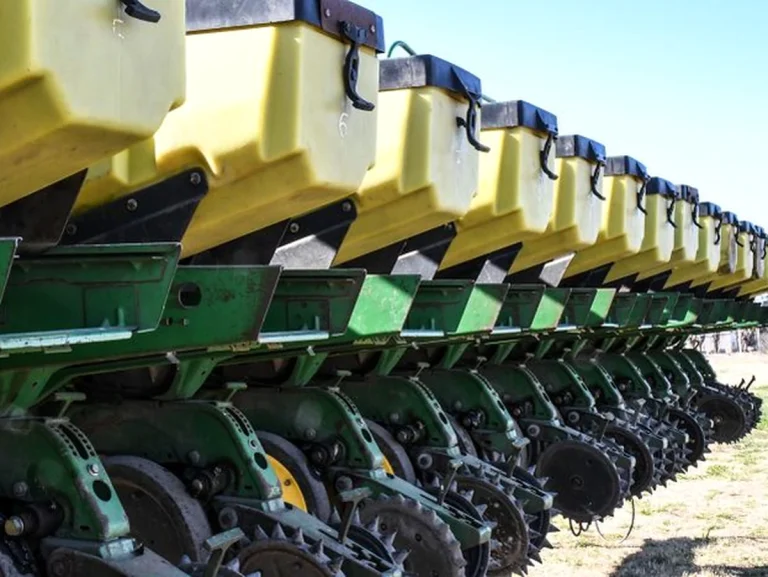 Fila de sembradoras agrícolas amarillas y verdes en el campo