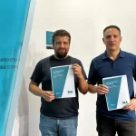 Dos hombres sosteniendo documentos en una presentación de ELA