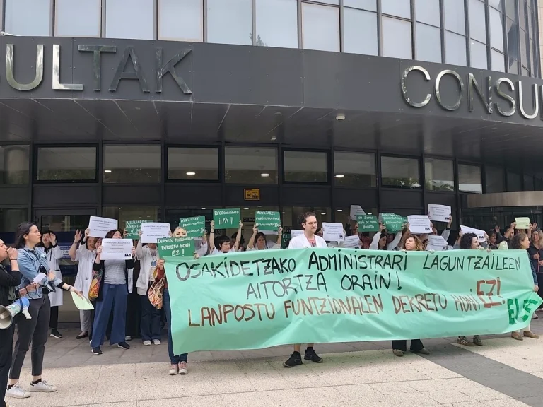 Protesta de auxiliares administrativos con pancartas frente a un edificio