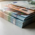Billetes de euro apilados sobre una superficie clara.