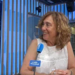 Mujer sonriente en un estudio de radio con micrófono azul