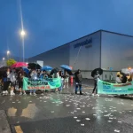 Grupo de trabajadores con paraguas protestando frente a Ormazabal.