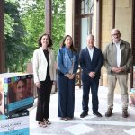 Cuatro personas posando junto a carteles de cursos de verano